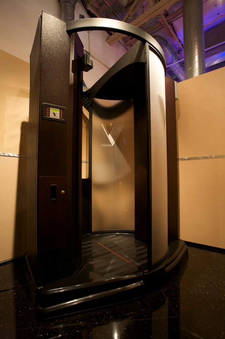 A room with a large metal door and a black stand.