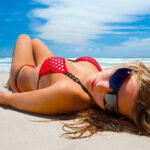 A woman laying on the beach in her bikini
