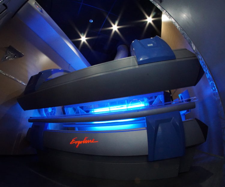 A tanning bed with blue lights and a black background