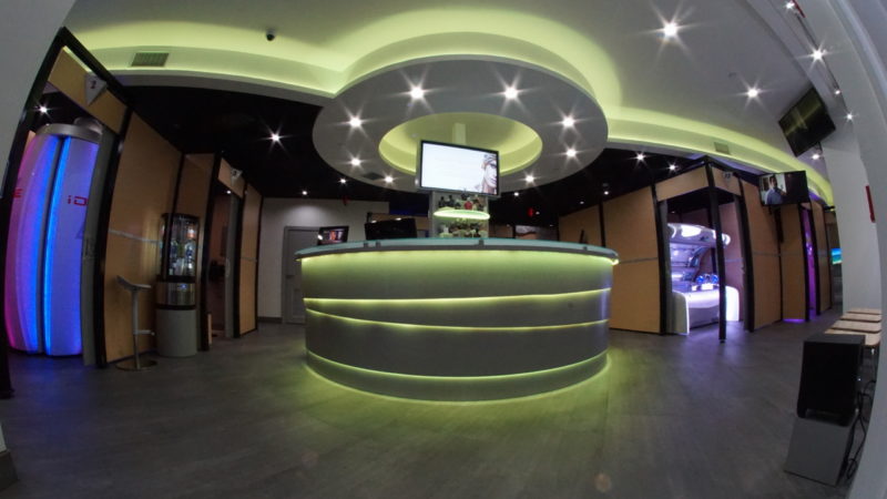 A large round reception desk with lights on the ceiling.