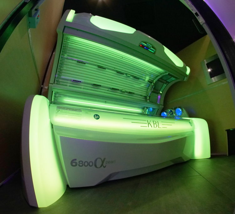 A tanning bed with green lights in the back.