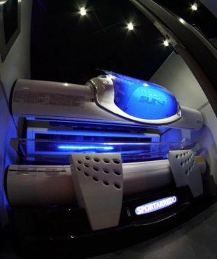 A tanning bed with blue lights in the room.