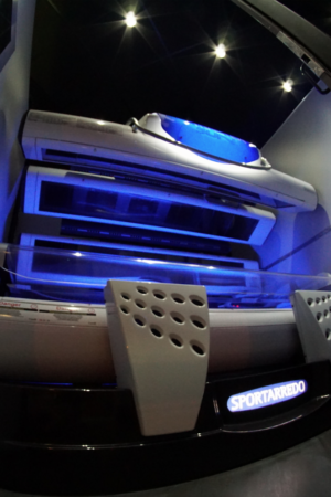 A tanning bed with blue lights and remote controls.