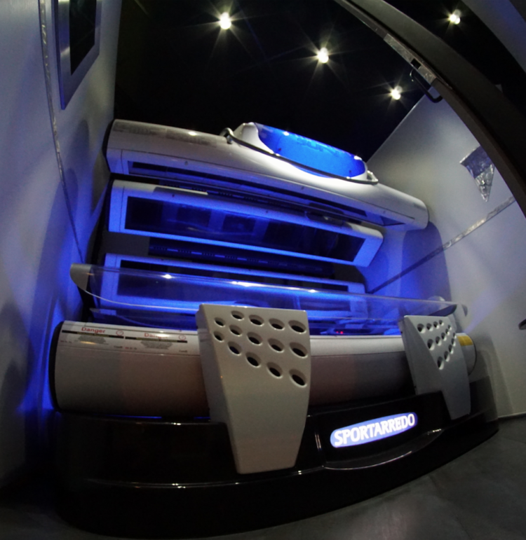 A tanning bed with blue lights and remote controls.