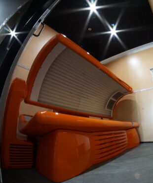 A tanning bed in an orange room with lights.