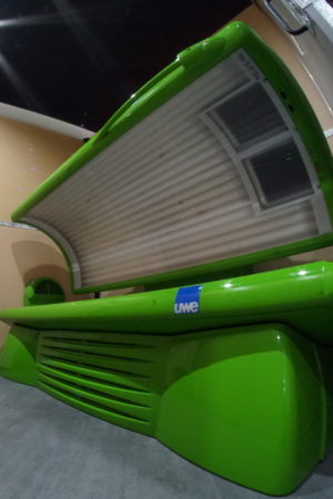 A green bench with an open tanning bed in the back.