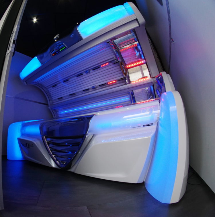 A white tanning bed with blue lights on it.