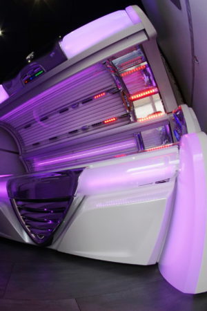 A white tanning bed with purple lights in the corner.