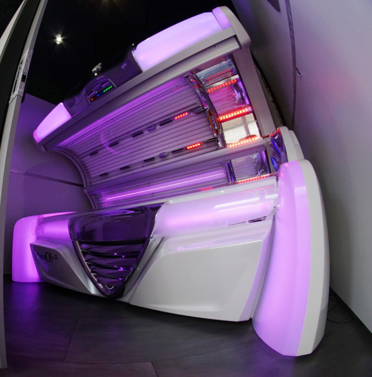 A white tanning bed with purple lights in the corner.