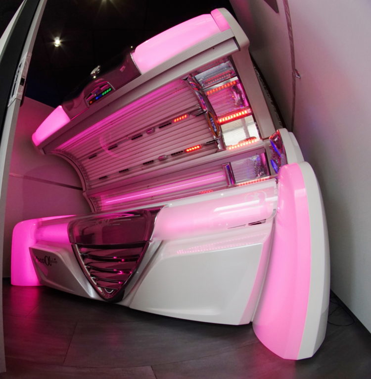 A white tanning bed with pink lights in it.