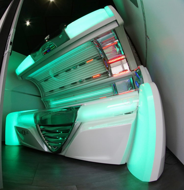 A white tanning bed with green lights on it.