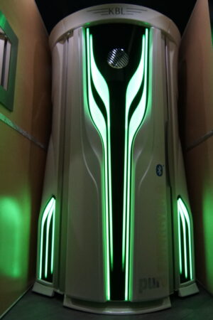 A green light is on the side of a building.