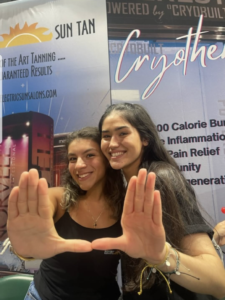 Two women standing next to each other holding their hands up.