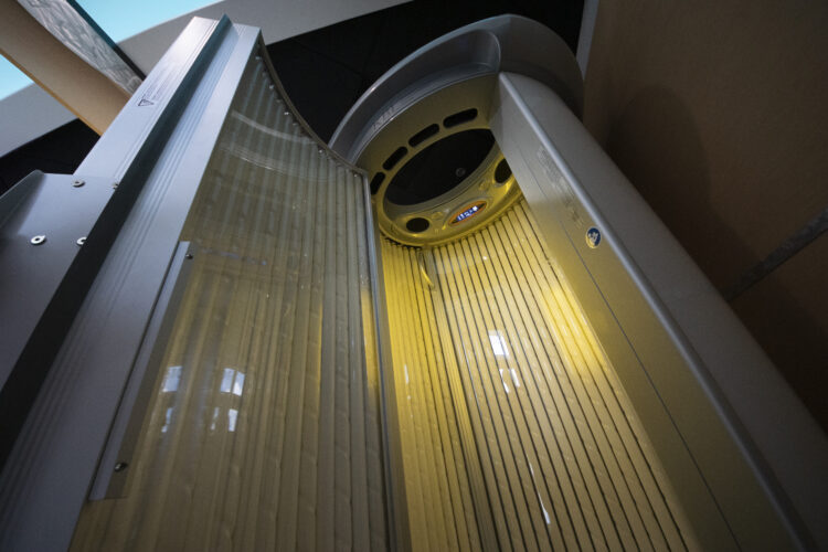 A yellow and silver tanning bed with a light on.
