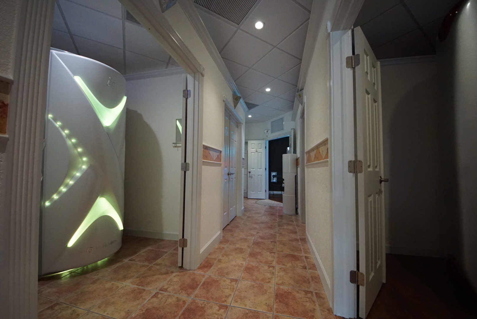 A hallway with many doors and lights on the wall.